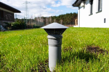 Ein graues Entlüftungsrohr aus einer Haushaltskläranlage ohne Abfluss im Garten.