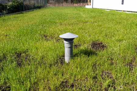 Photo for A gray vent pipe from a household septic tank without a drain located in the garden. - Royalty Free Image