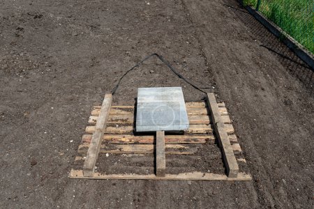 Photo for Leveling the chernozem in the yard with a pallet weighted with a concrete cube, preparing for sowing the lawn. - Royalty Free Image