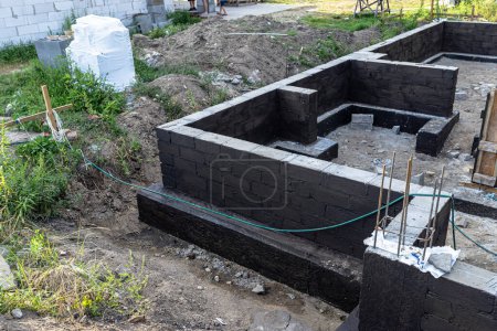 Photo for Footings made of concrete blocks painted with black dispersion asphalt-rubber mass, reinforced concrete pillars visible. - Royalty Free Image