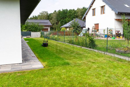 Cortando hierba con una cortadora eléctrica, con una anchura de corte de 44 cm, hileras cortadas visibles.