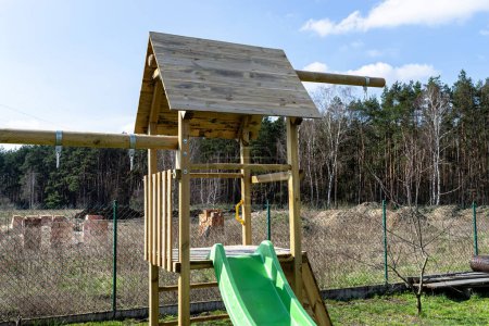 A childrens playground in the garden is made of unpainted wood.