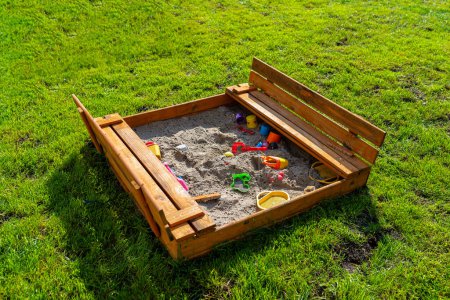 A square-shaped playground made of a wooden closed box, the box is open.