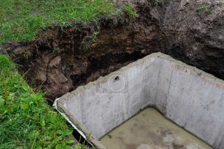 Concrete septic tank with a capacity of 10 m3 located in the garden next to the house, visible waterproof glue for the cover.