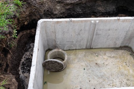 Concrete septic tank with a capacity of 10 m3 located in the garden next to the house, without a cover.