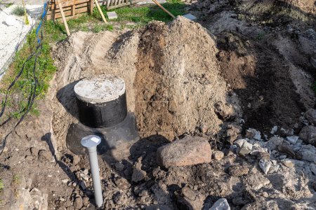 Téléchargez les photos : Utilisation d'une excavatrice pour enterrer une fosse septique en béton de 10 m3 située dans le jardin à côté de la maison. - en image libre de droit