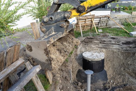 Using an excavator to bury a 10 m3 concrete septic tank located in the garden next to the house.