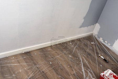 The vinyl floor is protected with foil before painting and covered with painters tape.