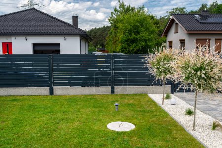 Téléchargez les photos : A modern panel fence in anthracite color, a visible sliding gate to the garage and a wicket with a letterbox. - en image libre de droit
