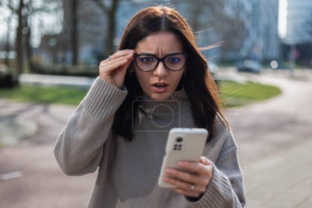 Téléchargez les photos : Femme choquée recevant un appel arnaque tenant ses lunettes. - en image libre de droit