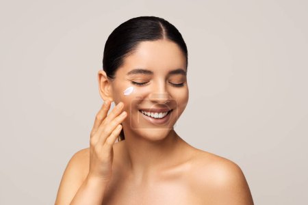 Photo for Seasonal face skin protection. Beauty shot of gorgeous multiracial woman with amazing smile applying cream on her face. - Royalty Free Image