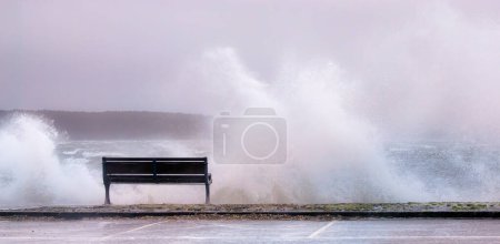 Stormy Encounter: Seaside Bench und die Wut der Natur. Dieses eindrucksvolle Foto fängt die rohe Kraft der Natur ein, als sich ein Sturm an der Küste von Poole, Großbritannien, entlädt.. 