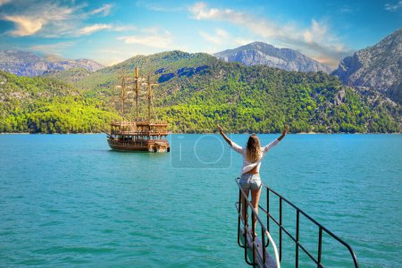 Photo for Girl with outstretched hands on the bow of a boat floating on the azure water - Royalty Free Image