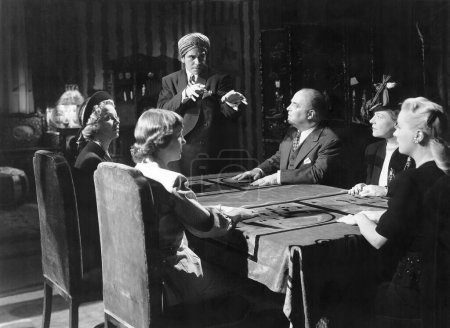 Foto de Hombre practicando espiritismo con gente sentada en la mesa de comedor - Imagen libre de derechos