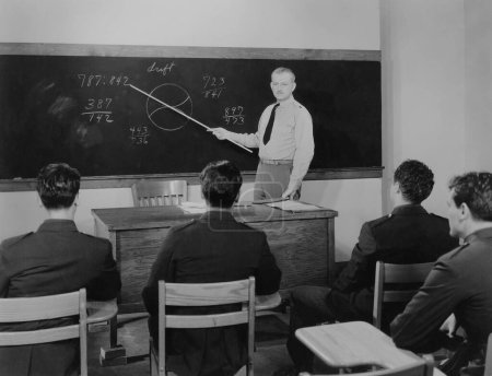 Foto de Oficial señalando la ecuación en pizarra mientras enseña a los aprendices sobre la fuerza aérea en el aula - Imagen libre de derechos