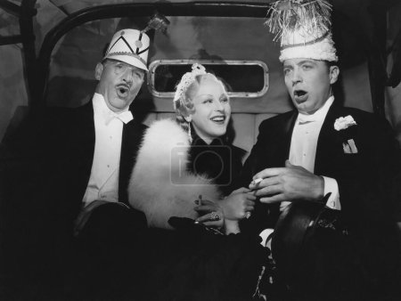 Foto de Alegre amigos con sombreros sentados en el coche va a la fiesta - Imagen libre de derechos