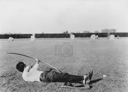 Foto de Longitud total del arquero macho acostado en la hierba apuntando al objetivo - Imagen libre de derechos