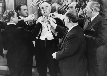 Foto de Grupo de hombres de negocios que ofrecen fósforos encendidos al gerente fumando cigarro en la fiesta - Imagen libre de derechos