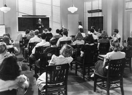 Foto de Vista trasera de jóvenes estudiantes de ambos sexos sentados con profesores en el aula de la universidad - Imagen libre de derechos