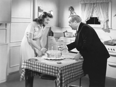 Foto de Dos personas preparan un pastel de cumpleaños en la cocina. - Imagen libre de derechos
