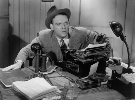 Foto de Hombre de negocios preocupado mirando hacia otro lado mientras está sentado con la máquina de escribir en el escritorio en la oficina - Imagen libre de derechos