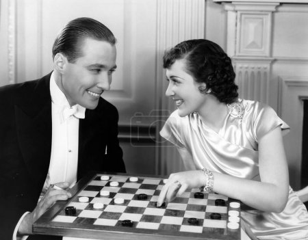 Foto de Feliz joven pareja jugando damas juntos en casa - Imagen libre de derechos
