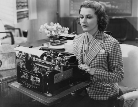 Foto de Hermosa joven asistente personal femenino utilizando máquina de escribir en el escritorio en la oficina - Imagen libre de derechos