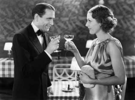 Foto de Sonriendo hombre maduro tostando bebida con la mujer de pie en el restaurante - Imagen libre de derechos