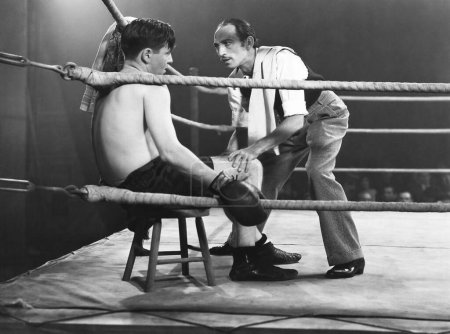 Foto de Entrenador alentador boxeador sentado en la esquina del anillo durante el partido - Imagen libre de derechos