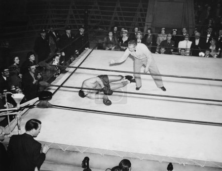 Foto de Árbitro cuenta atrás nocaut en el ring de boxeo rodeado de espectadores - Imagen libre de derechos