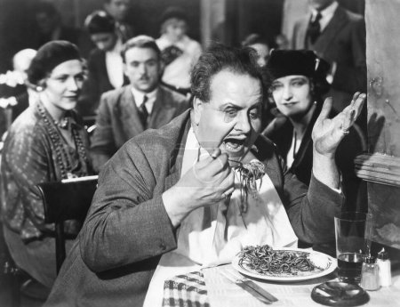 Foto de La gente viendo a un hombre maduro comiendo pasta de espagueti en el restaurante - Imagen libre de derechos