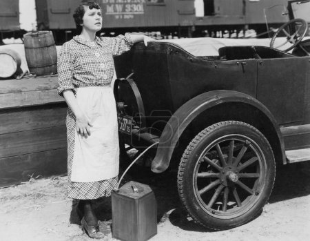 Foto de Longitud completa de la mujer preocupada de pie en coche y contenedor en el día soleado - Imagen libre de derechos
