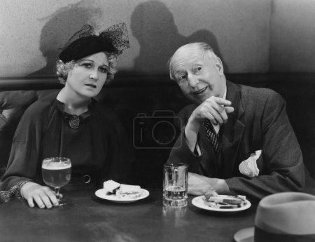 Foto de Sonriente hombre mayor sentado con la mujer madura en la mesa en el restaurante - Imagen libre de derechos
