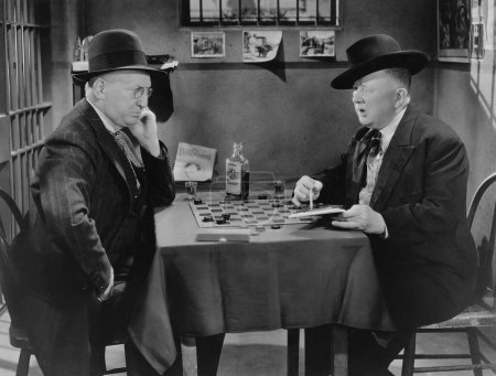 Foto de Hombre maduro mostrando bloc de notas al oponente mientras juega damas en la mesa - Imagen libre de derechos