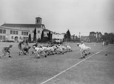 Foto de Equipos de fútbol americano del adolescente que compiten entre sí en el campo contra el cielo - Imagen libre de derechos