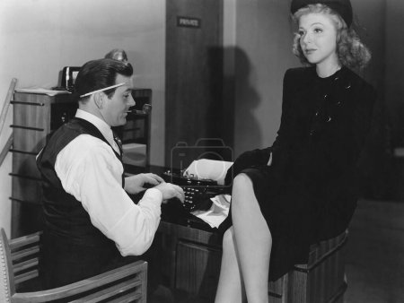 Foto de Empresario usando máquina de escribir mientras colega sentada en el escritorio en la oficina - Imagen libre de derechos