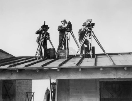 Low angle view of cameramen standing on roof against sky