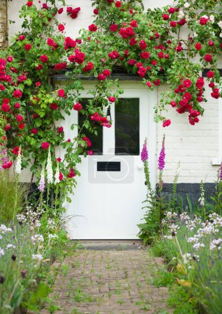 Photo for BUCKINGHAMSHIRE, UK - June 03, 2022. Exterior of English cottage house and garden with climbing roses around front door. England, UK - Royalty Free Image