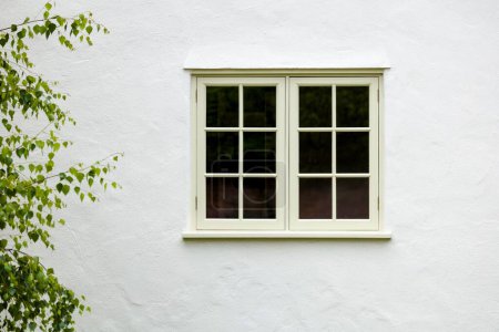 Britisches Haus außen mit hölzernem Flügelfenster und weißer Wandverkleidung