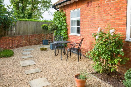 Royaume-Uni jardin patio design. Aménagement paysager dur avec pierre York marches en gravier et une table et chaises de bistrot en métal.