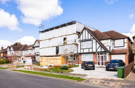 Foto de LONDRES, Reino Unido - 11 de abril de 2023. Renovación de la casa, casa suburbana semi-adosada cubierta con hojas de andamio. - Imagen libre de derechos