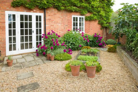 UK house and garden with patio and French doors. Cottage or courtyard garden (backyard) with gravel and York stone paving