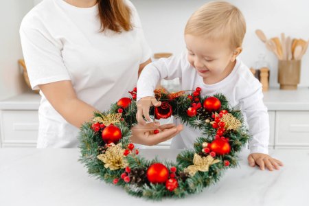 Photo for Little helper son helps mom with Christmas decorations. - Royalty Free Image