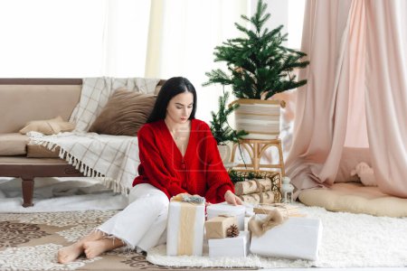 Photo for A girl opens presents. a young girl sitting among Christmas and New Year presents. - Royalty Free Image