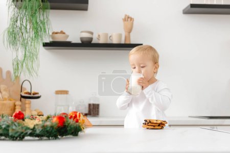 Photo for Christmas morning. A child wakes up and drinks milk and Christmas cookies in the kitchen. - Royalty Free Image