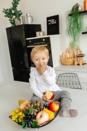 Photo for A child picks his nose in the kitchen. Reducetarian Eating Enjoying Plant-Based Food - Royalty Free Image