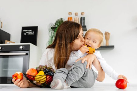 Photo for Happy Family Mom hugging baby and eating apples and healthy food. Reducetarian Eating Enjoying Vegetable Food. - Royalty Free Image