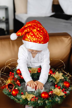 Photo for A boy opens a Christmas present for Christmas. A child sits on an armchair and holds a gift. - Royalty Free Image