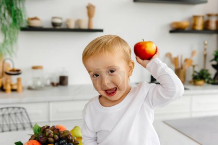 Photo for A happy child holding a red apple in his hand and waving to the camera. - Royalty Free Image