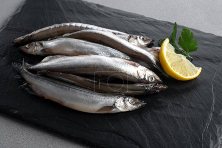 Photo for Raw fresh fish capelin with lemon. Gray background. Top view - Royalty Free Image